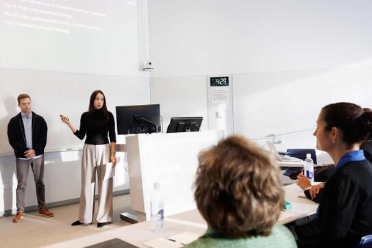 Students in front of a presentation in a classroom, addressing the shark tank judges in the Legal Financial Arbitrage class