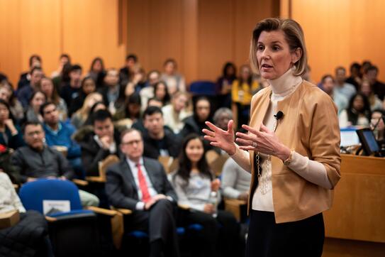 A guest lecturer speaks to a packed hall of students